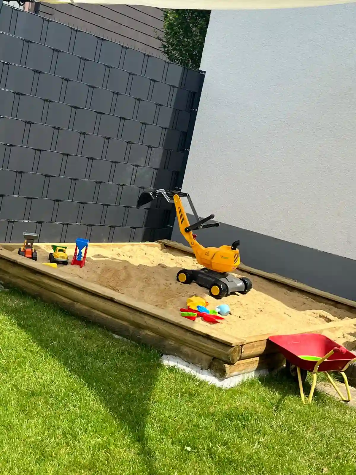 Sandkasten mit Spielzeugbagger im Garten